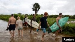 La gente camina a través de una ensenada de playa inundada mientras la tormenta tropical Debby se mueve desde Georgia hacia el Atlántico Norte en Isle of Palms, Carolina del Sur, EE.UU., 6 de agosto de 2024. REUTERS/Marco Bello